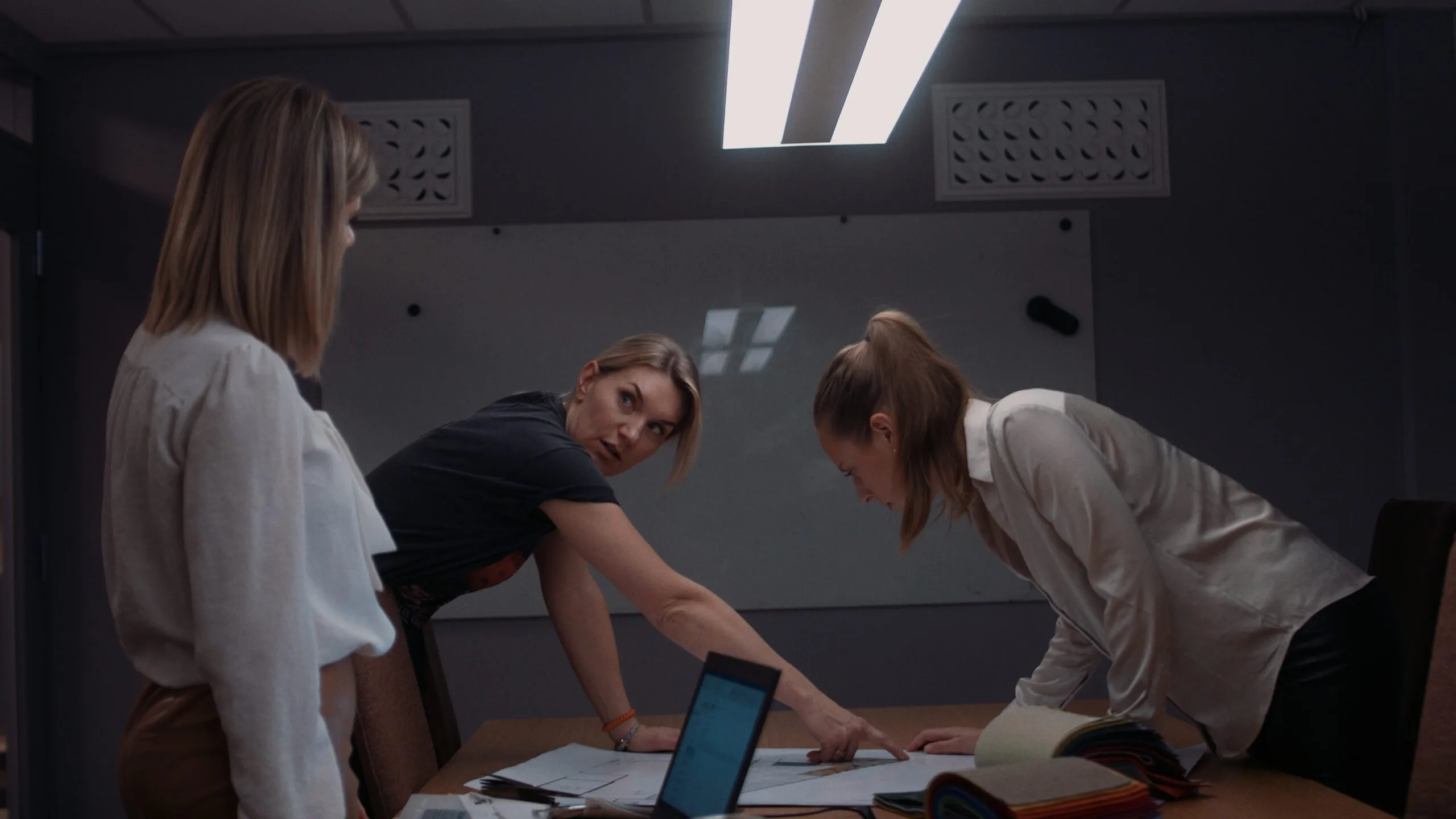 Tre damer står å ser på et ark over et bord.